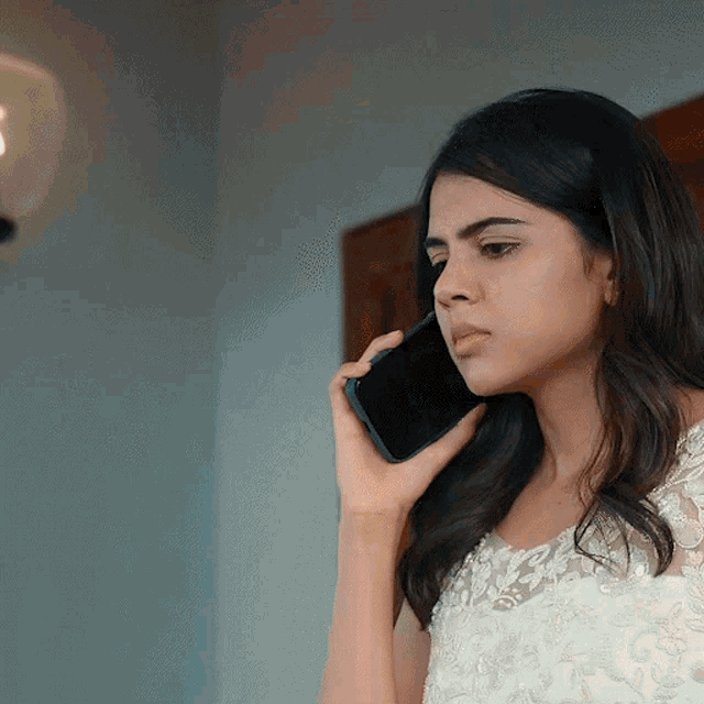 a woman in a white dress is talking on her phone