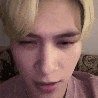 a close up of a person 's face with a pink shirt on .