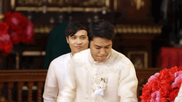 a man in a white shirt with a flower on his chest