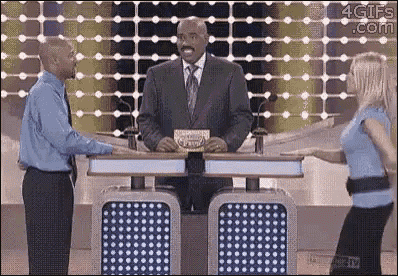 a man in a suit and tie is standing in front of a woman on a game show .