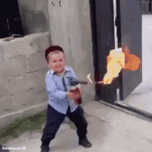 a young boy is holding a fire extinguisher in his hand and making a funny face .
