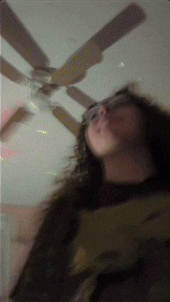 a blurry picture of a woman with a ceiling fan behind her