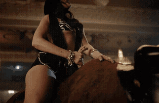 a woman in a bikini is riding a brown horse
