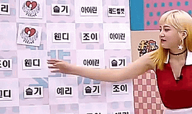 a woman in a red shirt is standing in front of a wall with korean writing on it
