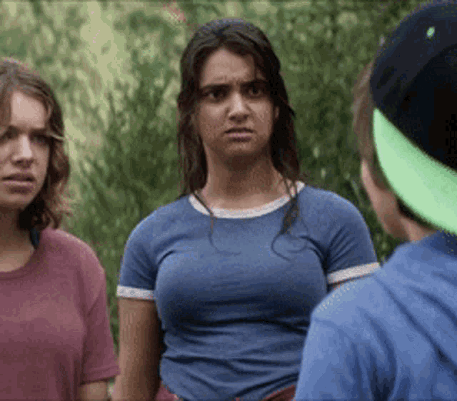 a woman in a blue shirt is standing next to two other women