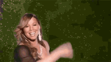 mariah carey is wearing a black dress and a diamond necklace while dancing on stage .