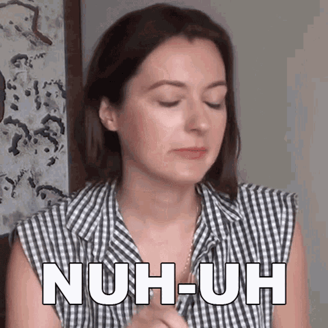 a woman wearing a plaid shirt says nuh-uh in white letters