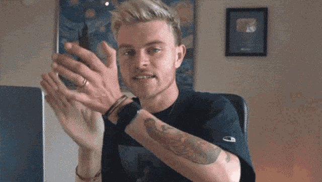 a man with a tattoo on his arm is clapping
