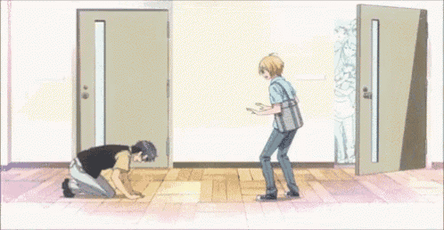 a man is kneeling down in front of a door while another man stands in front of it .