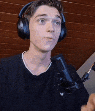 a young man wearing headphones stands in front of a microphone