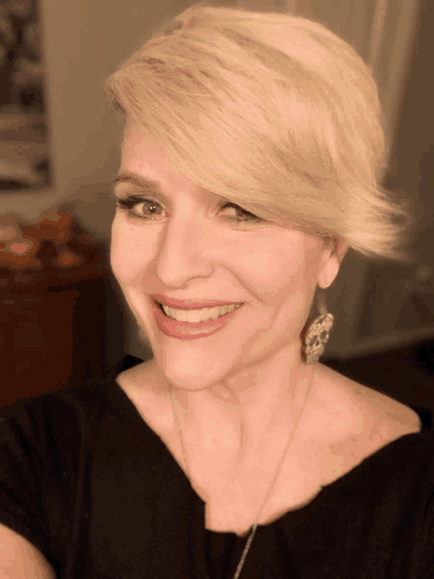 a woman with blonde hair is smiling and wearing a black shirt