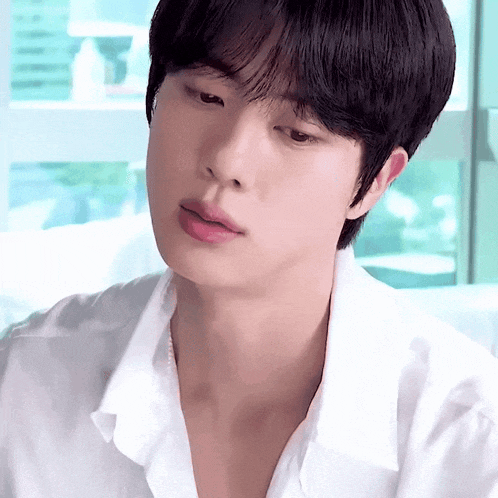 a close up of a young man 's face with a white shirt on