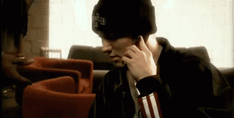a man wearing a beanie is talking on a cell phone while sitting on a couch .