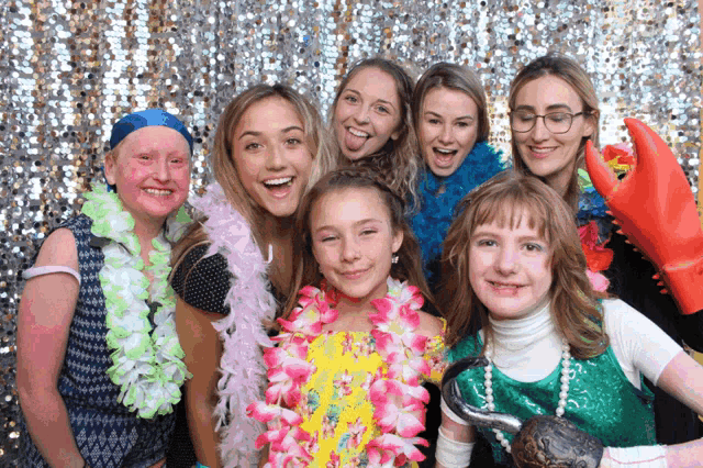 a group of girls posing for a picture in front of a silver sequined backdrop