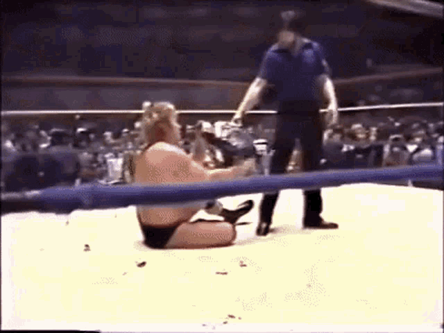 a wrestler is kneeling on the ground in a wrestling ring .