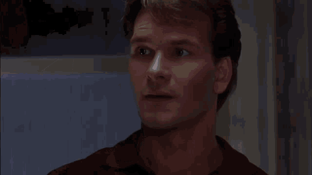 a close up of a man 's face in a red shirt looking down .