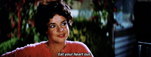 a woman in a red shirt is talking to another woman and says eat your heart out .