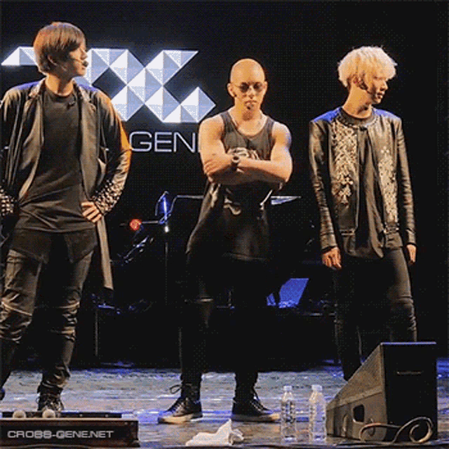 three men standing on a stage in front of a gen logo