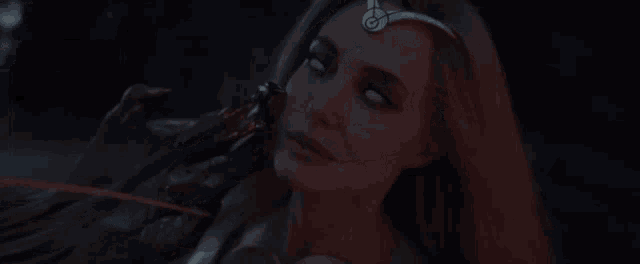a woman with white eyes and a crown on her head is looking at the camera .
