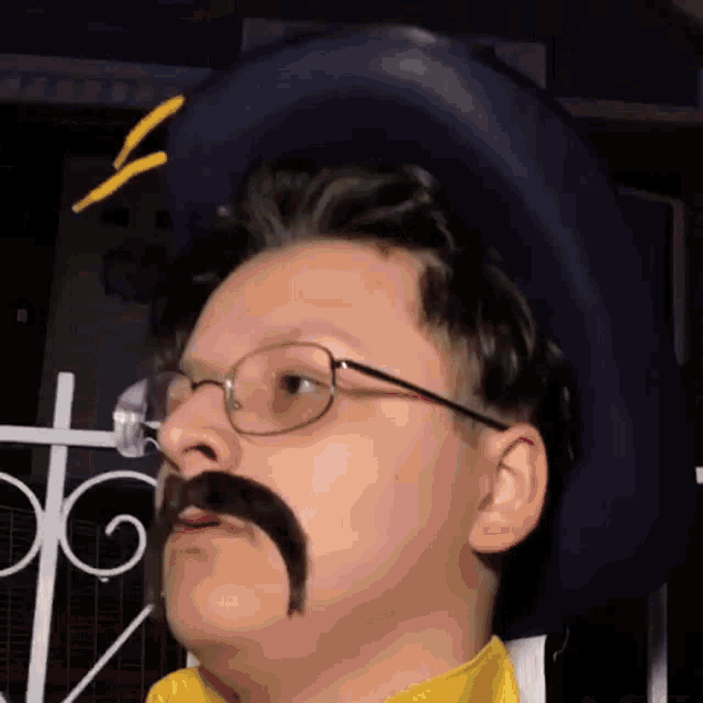 a man with a mustache and glasses is wearing a cowboy hat