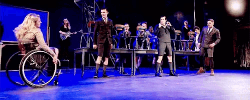 a woman in a wheelchair is standing on a stage in front of a group of people .