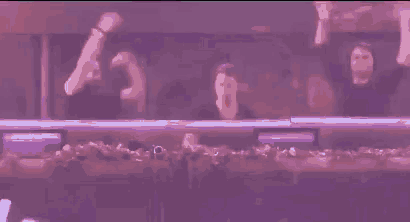 a group of men are dancing in a dark room with purple lights .