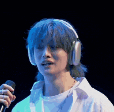a woman with blue hair is wearing headphones and holding a microphone .