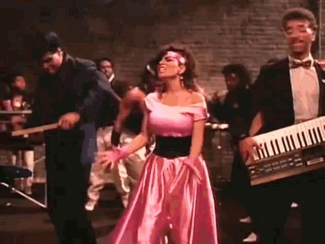 a woman in a pink top is dancing in a crowd