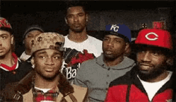 a group of men are posing for a picture with one wearing a red c hat