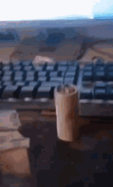 a blurred image of a computer keyboard with a cup on the desk