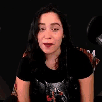 a woman is smiling in front of a microphone and wearing a black shirt .
