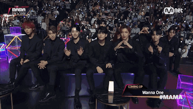 a group of young men are sitting in front of a crowd at a mnet event