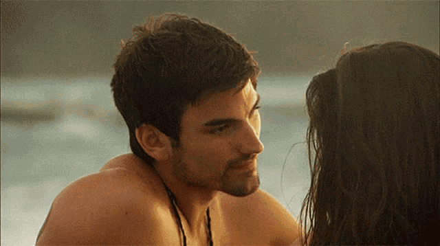 a man without a shirt is looking at a woman with long hair