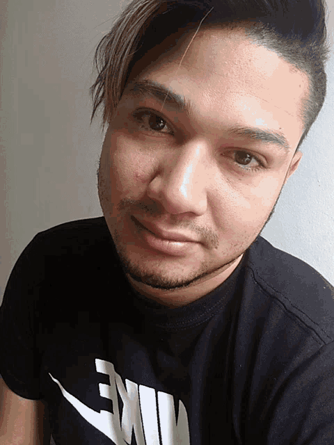 a man wearing a black nike t-shirt smiles for the camera