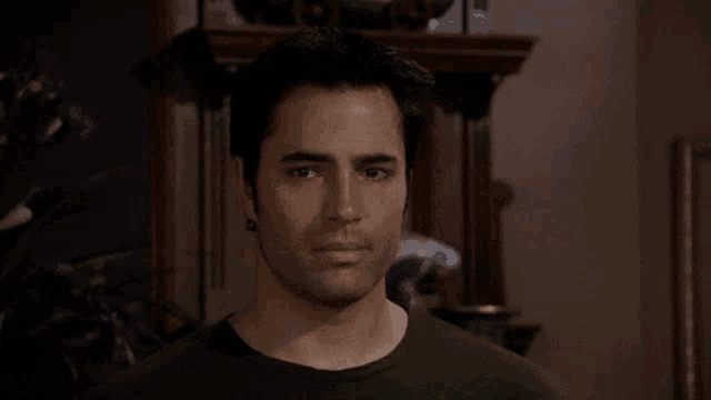 a man in a black shirt looks at the camera