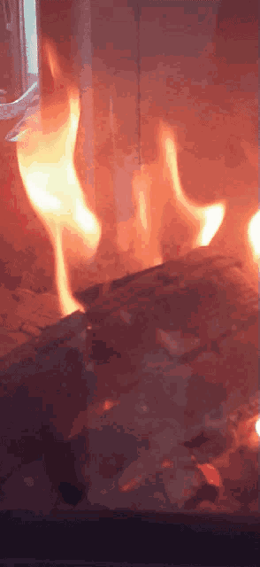a fire is burning in a fireplace with a brick wall behind it
