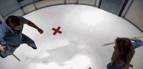 a man and a woman are standing on a white floor with a red cross on it