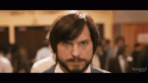 a man with a beard is standing in a crowded room .