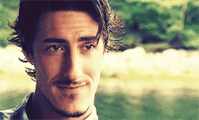 a man with long hair and a beard is smiling and looking at the camera