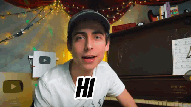 a young man sitting in front of a piano with a hi sticker on his shirt