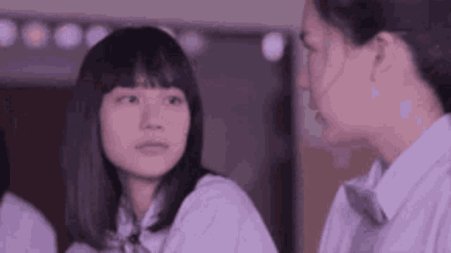 a group of girls are standing next to each other in a room and talking .