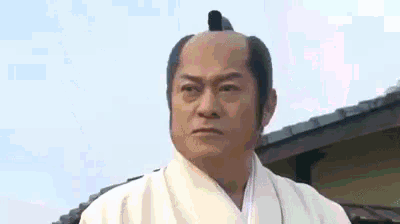 a man with a mohawk is wearing a white kimono and a white shirt .