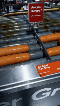 a sign that says " are you hungry " hangs above a row of hot dogs
