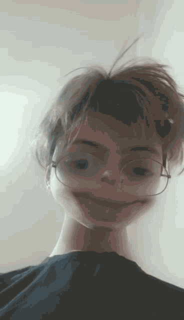 a young man wearing glasses and a black shirt is making a funny face .