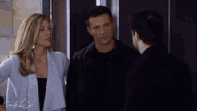 a man and a woman are standing next to each other in front of an elevator .