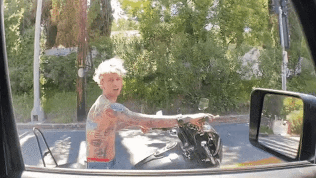a tattooed man is riding a motorcycle in a car window