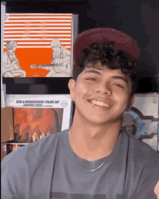 a young man wearing a hat is smiling in front of a sign that says ' reveal underground '