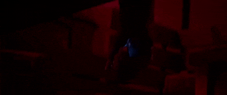a man is standing in the dark in a red light .
