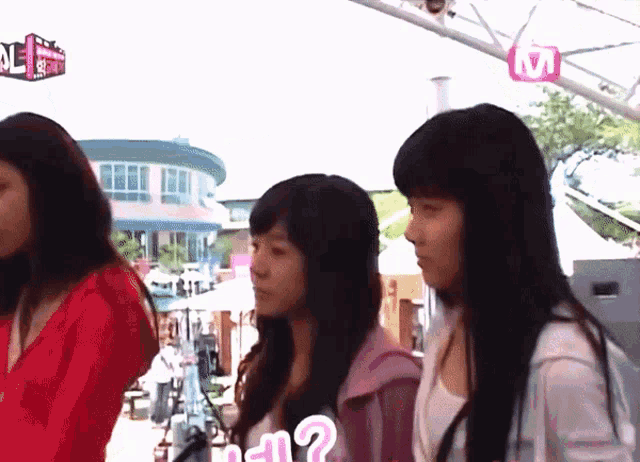 three girls are standing in front of a sign that says ' m ' on it