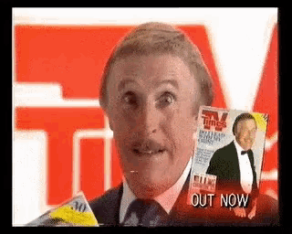 a man in a suit and tie is holding a magazine in front of his face .
